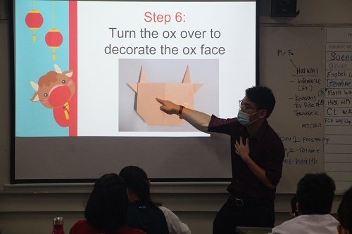 Students learning how to fold the origami Ox from the Powerpoint slides